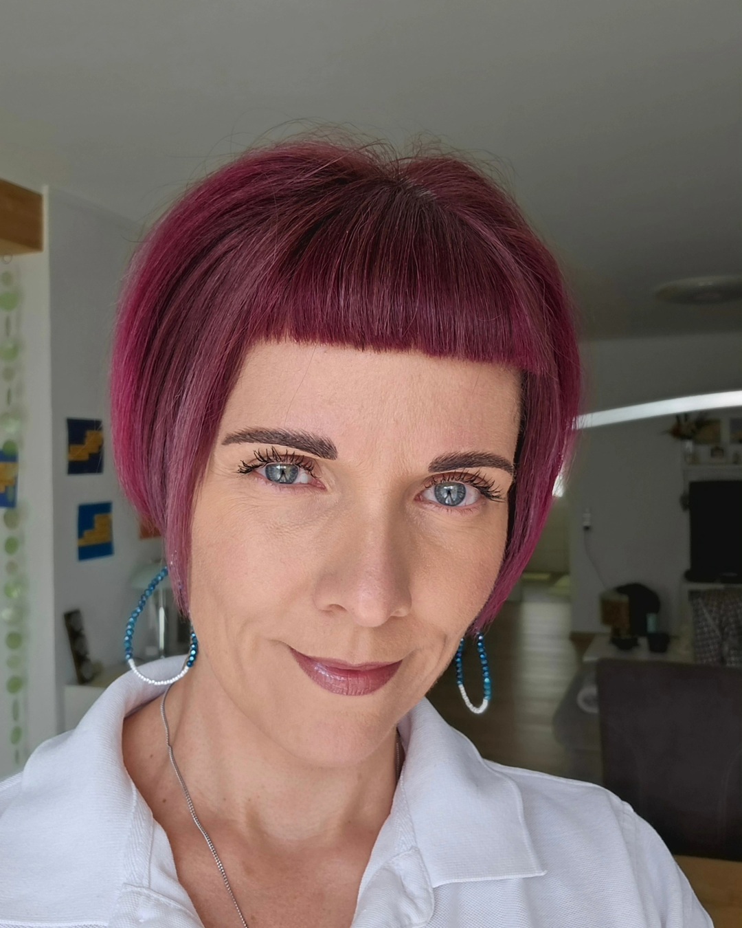 Woman with a sleek magenta pink Dutch boy haircut and straight baby fringe