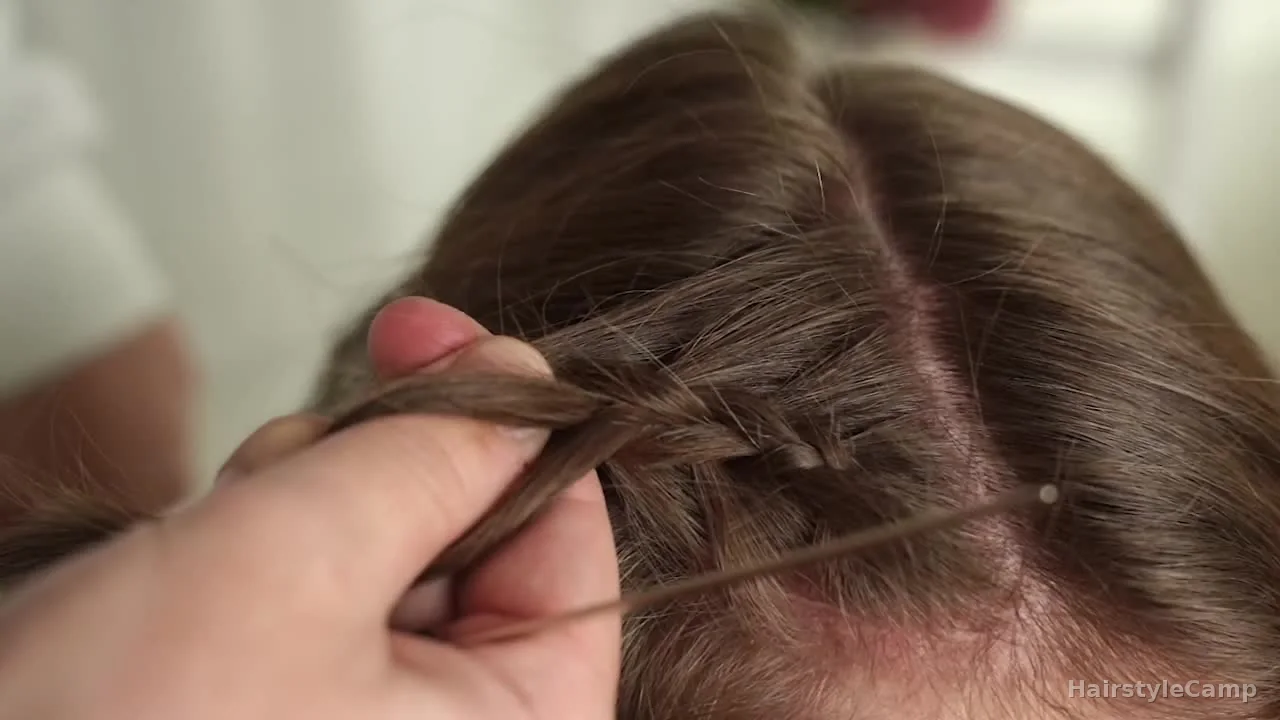 Outer braid strand crossing under the middle while the thumb anchors the braid close to the scalp.