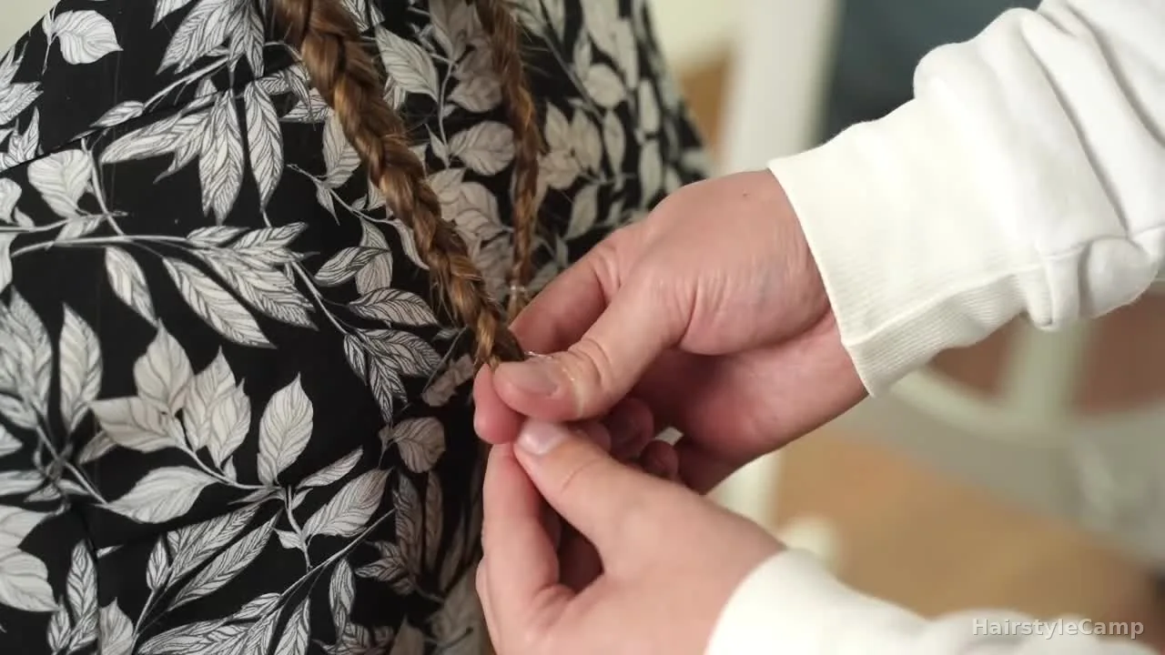 Clear polyband elastic being wrapped around the finished braid tail near the bottom.