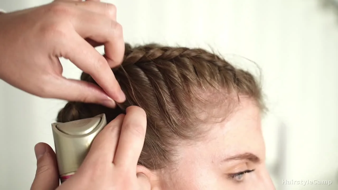 Hairspray being used on the finished braids while the smooth curved side of the can and fingertips press flyaways flat.