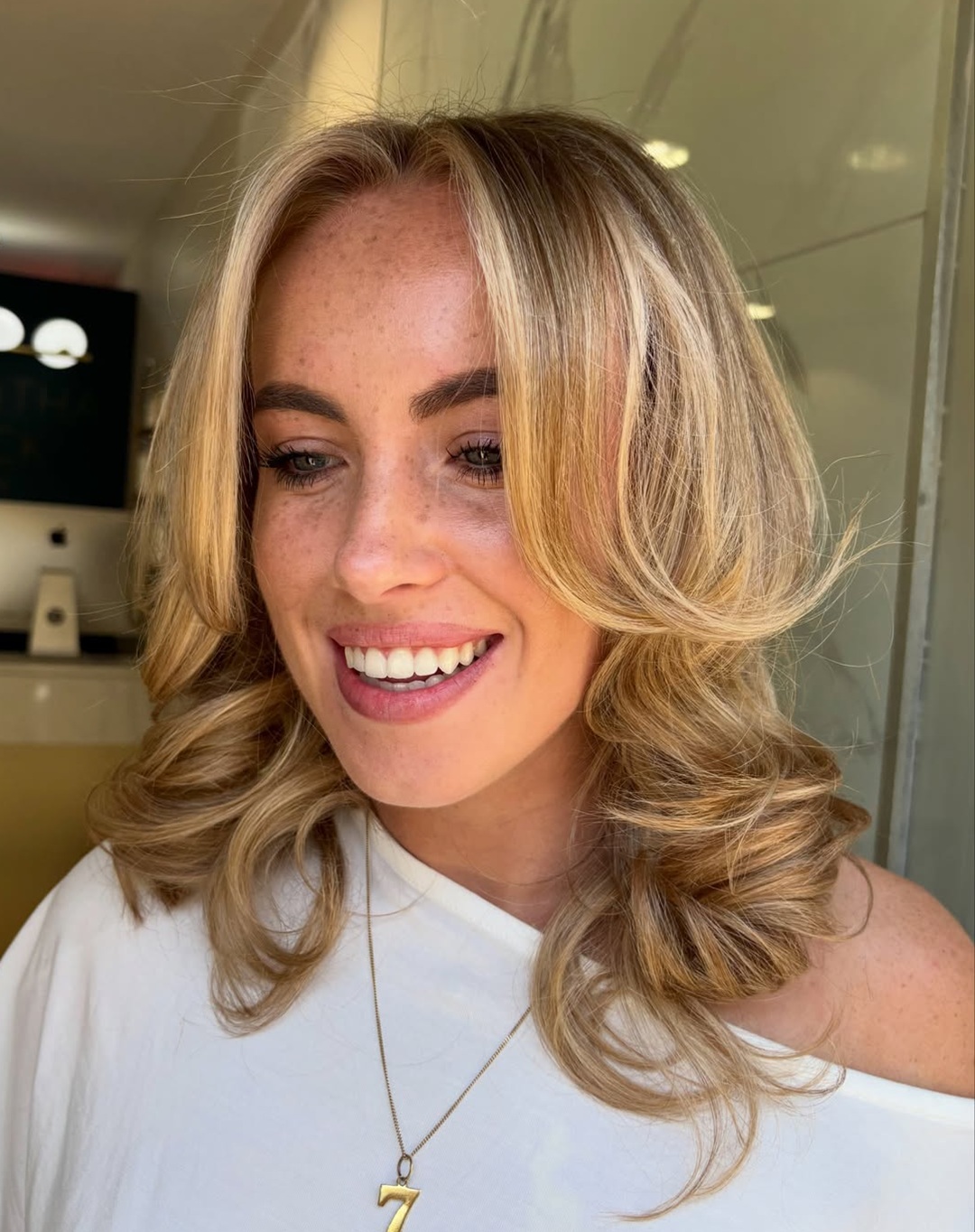 woman with sun kissed golden blonde highlights and sweeping curtain bangs