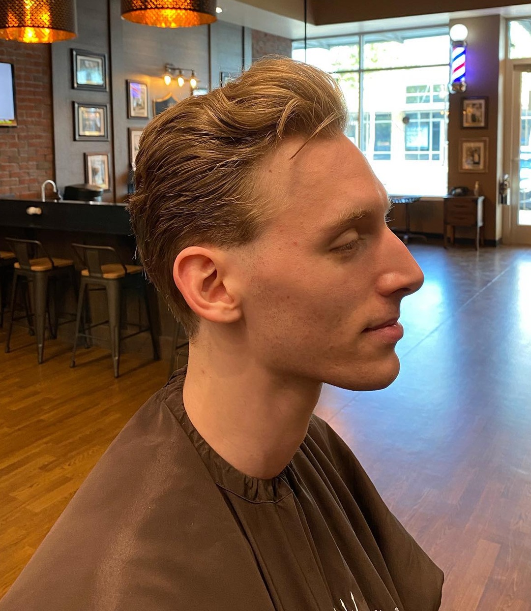 Side view of a man with a relaxed light brown messy pompadour haircut