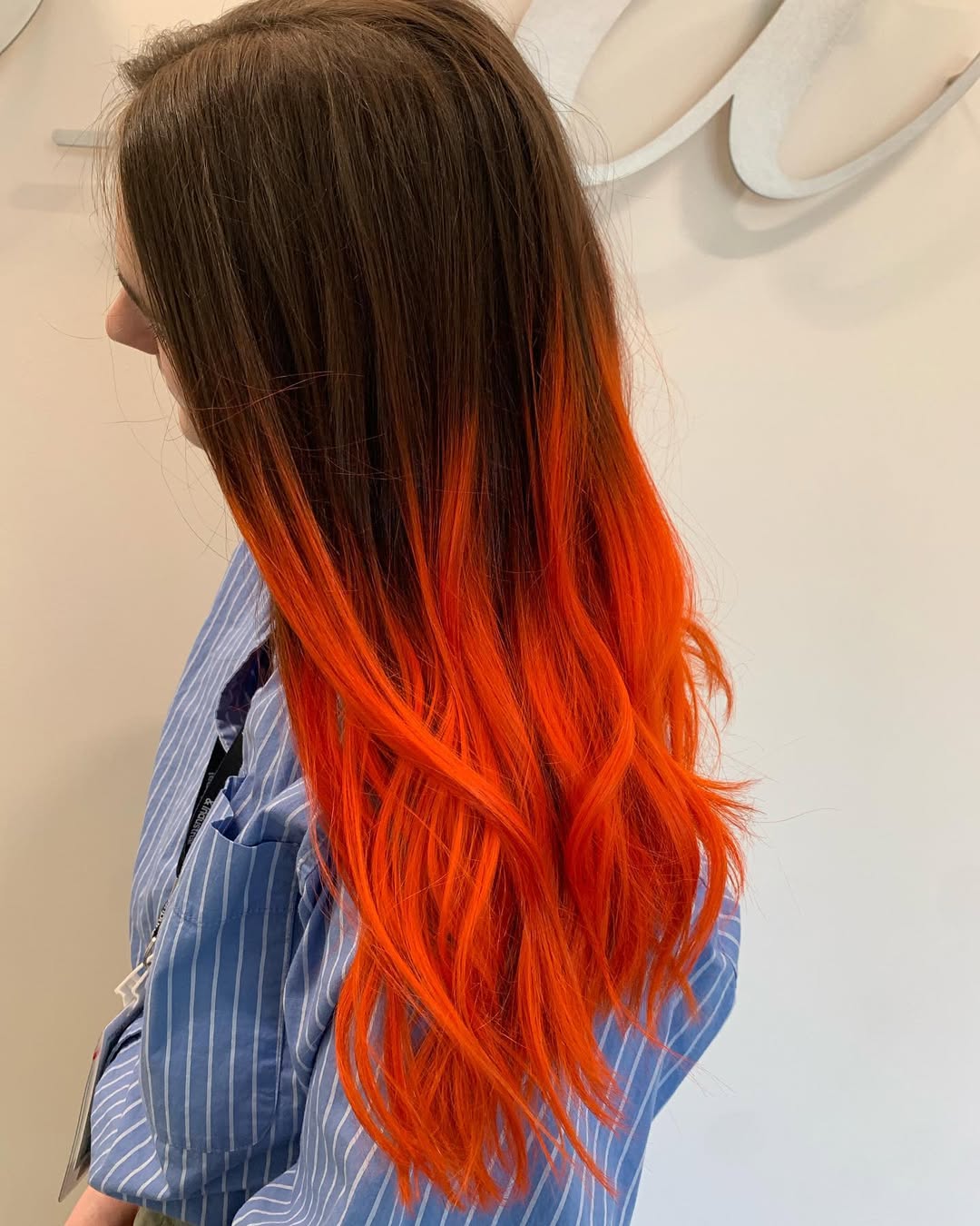 Long wavy dark hair featuring a vivid tangerine orange ombre