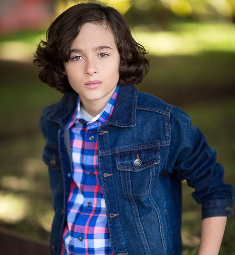 Young boy with a wavy, side-swept layered brunette cut