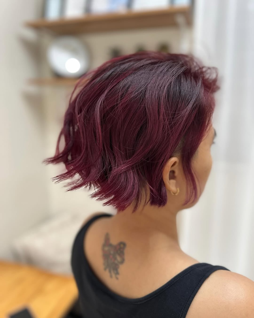 Side view of a woman with a short textured red wine bob cut
