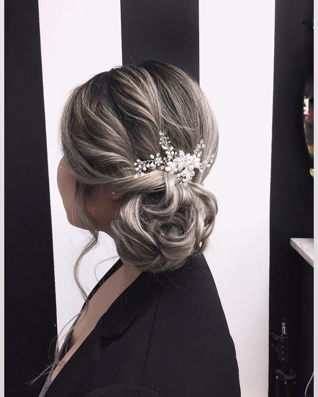Low textured wavy side bun updo adorned with a pearl and crystal hair pin