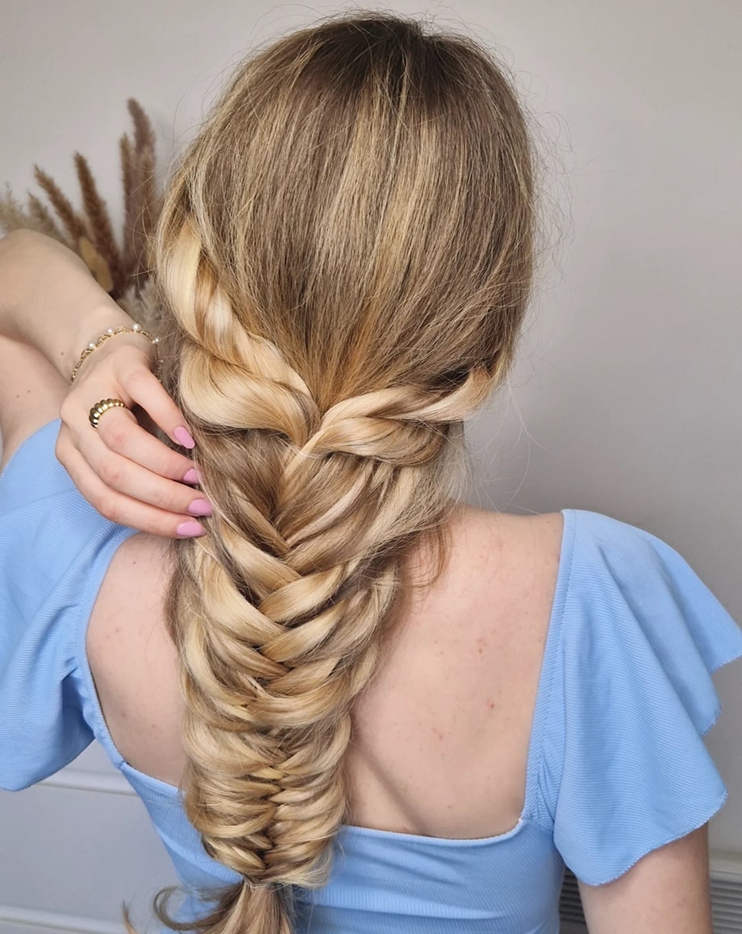 thick voluminous fishtail braid on long golden blonde hair with side twists,