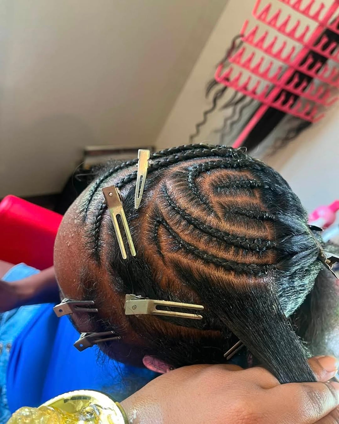 top view of kid' scurved cornrow braids pinned with metal clips, illustrating key styling mistakes to avoid like tight tension and improper clipping
