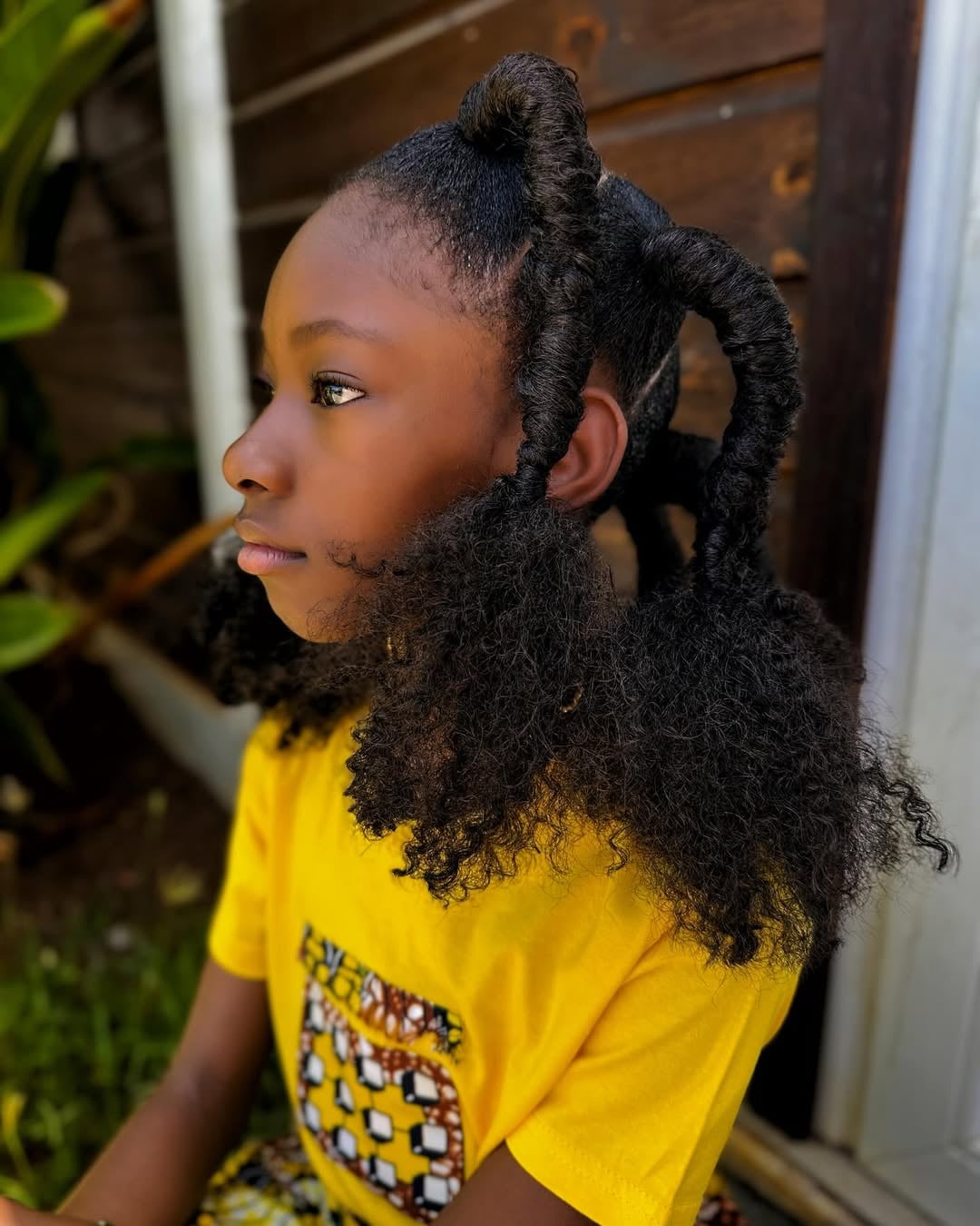 Little black girl styled in thread-wrapped looped ponytails with fluffy afro puff ends