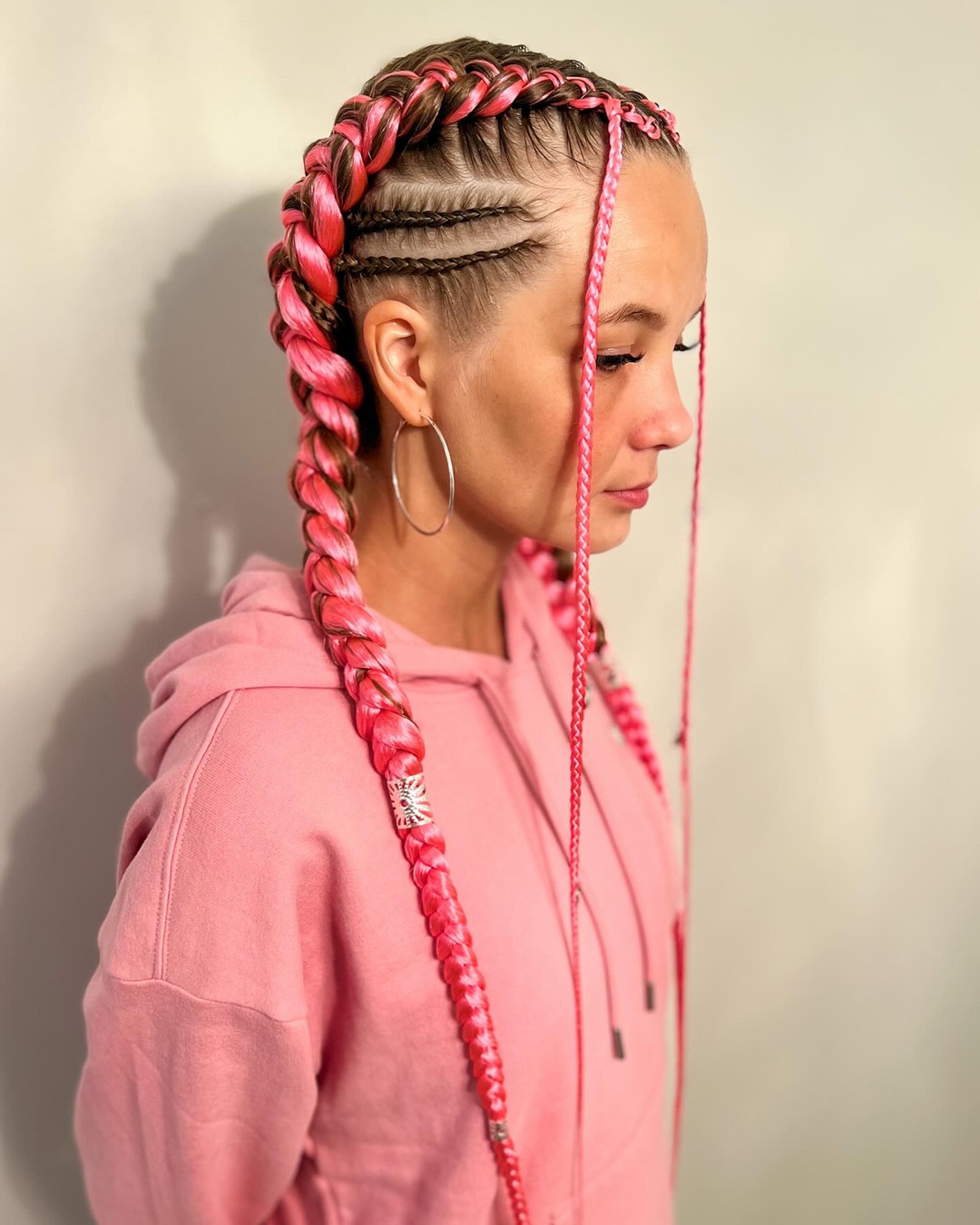 Two jumbo pink feed-in braids featuring side cornrows and face-framing accent braids