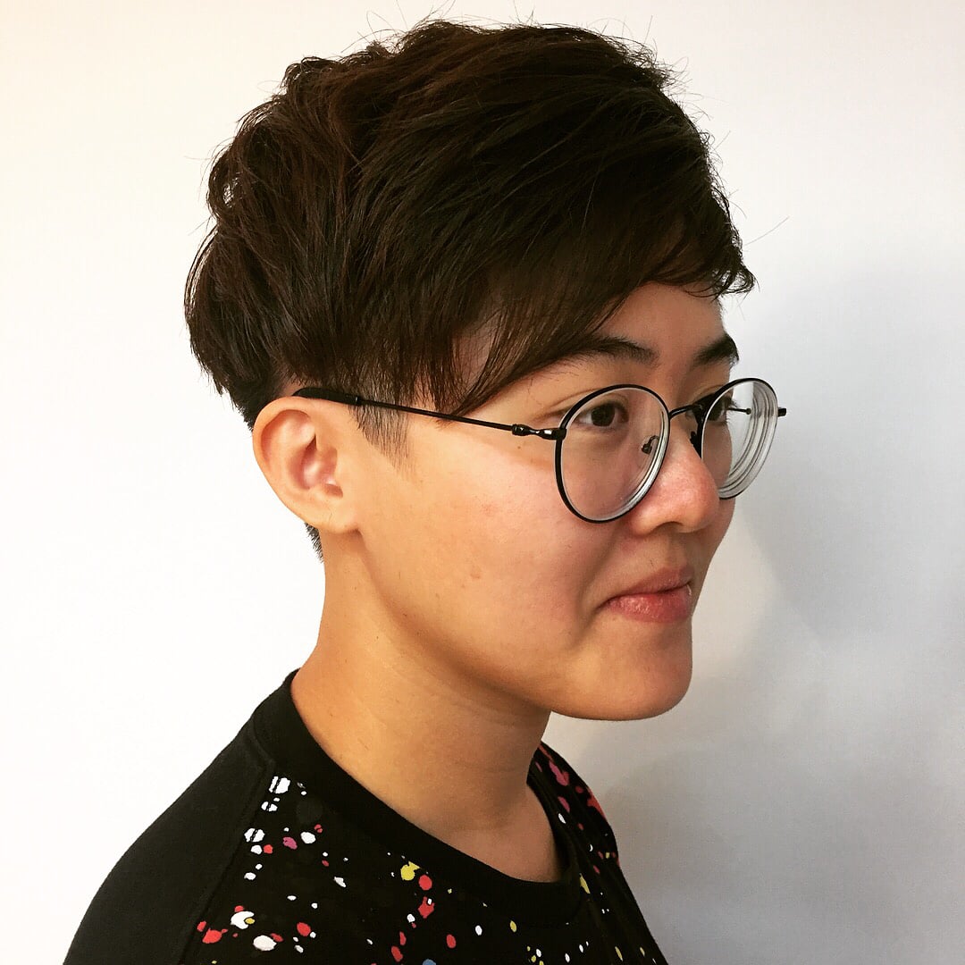 Asian woman wearing glasses with a dark brown undercut pixie cut and side-swept fringe