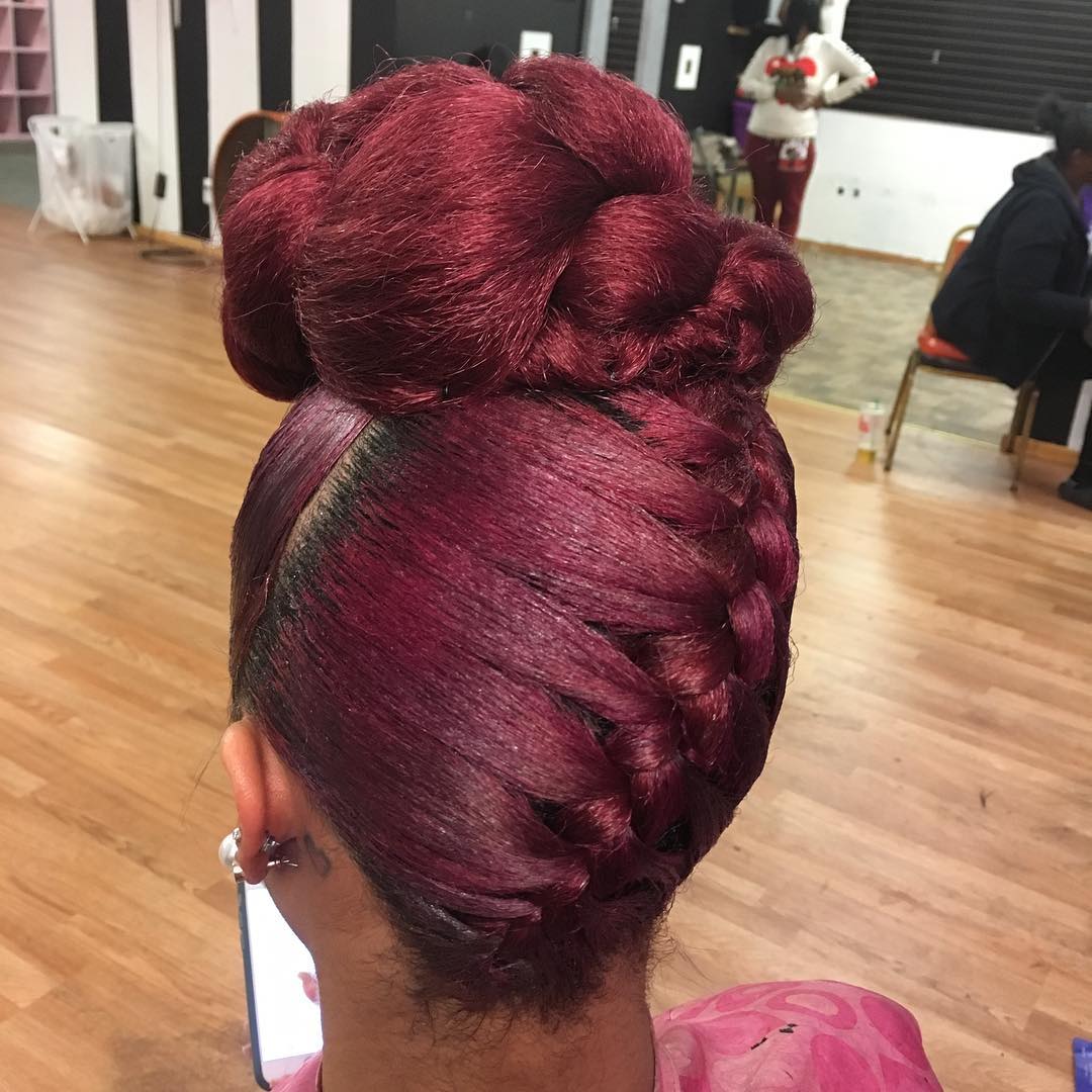 Burgundy upside-down French braid gathered into a high looped bun.