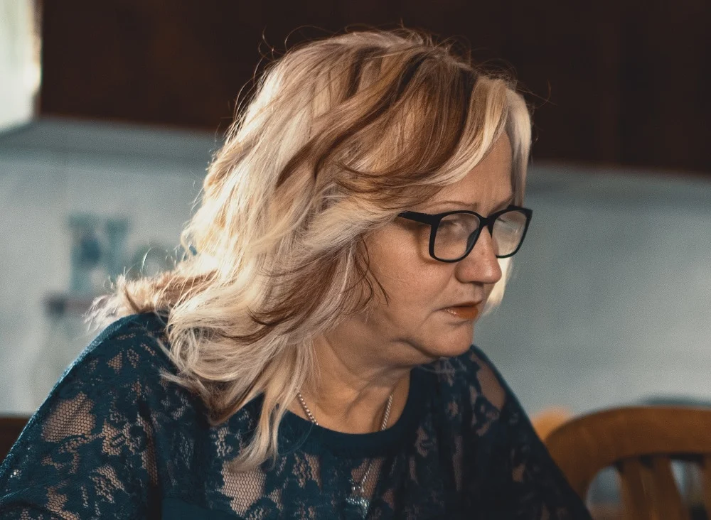 Wavy layered hairstyle for people over 50 with glasses