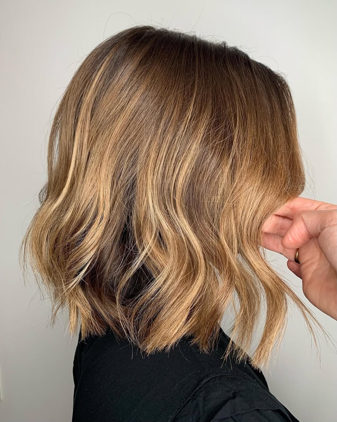 Woman with a wavy textured lob in warm chestnut blonde highlights