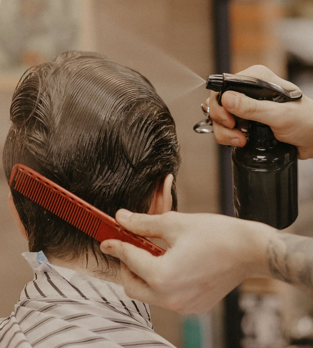 spraying water onto wet hair with a spray bottle and comb to get rid of a cowlick