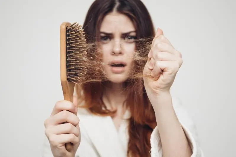 women checking hair brush for hairfall
