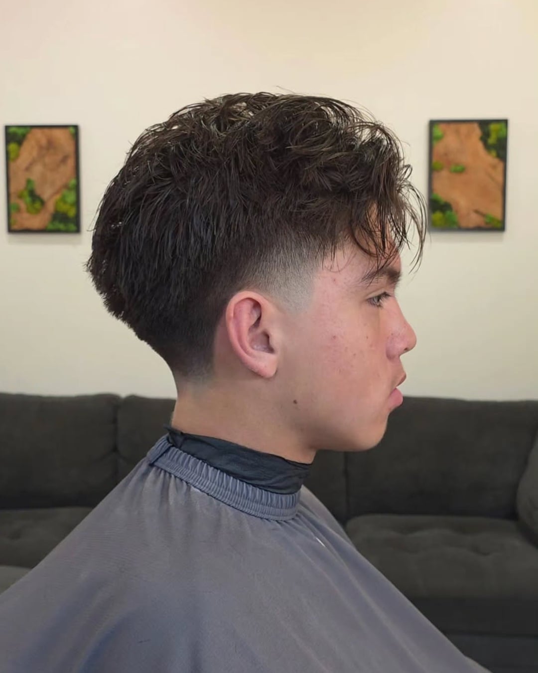 young man with wispy blowout hair featuring messy piecy fringe and a low taper fade